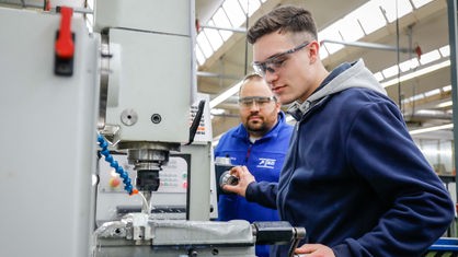 Ein männlicher Auszubildender in einem Metallberuf mit einem Ausbilder an einer Werkzeugmaschine im Berufsbildungszentrum der Remscheider Metall- und Elektroindustrie.