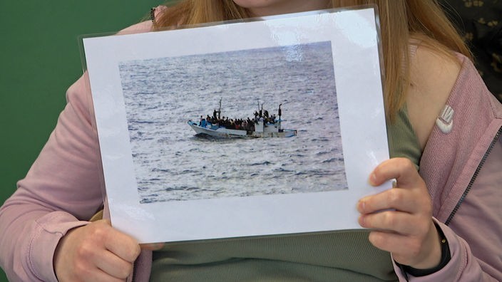 Schülerin Hannah zeigt im Politikunterricht ein Bild von einem Flüchtlingsboot