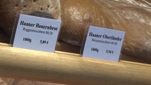 Eine Brotauslage mit zwei Preisschildern: "Haaner Bauernbrot" für 5,89€ und "Haaner Oberländer" für 5,49€.