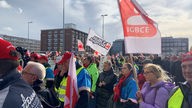 Etliche Demonstranten stehen mit gelben Westen in Leverkusen und halten Schilder hoch