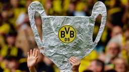 ein gebastelter Champions-League-Pokal mit dem BVB-Logo, im Hintergrund viele Menschen in gelb-schwarzen Trikots
