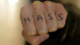 Pesnica sa tetovažom HASS (mržnja) na prstima