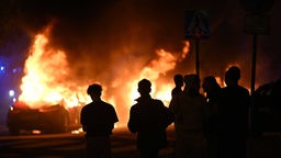 enschen sehen zu, wie Autos auf Ramels Vag in Rosengard, Malmö, nach einem Aufstand in den frühen Morgenstunden brennen, 04.09.2023. 