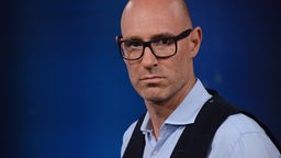 Lars Sänger, ein Mann mit Glatze und Brille mit dickem, schwarzen Rahmen, arbeitet als freier Journalist in Thüringen.