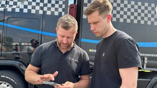 Zwei Männer schauen auf ein Smartphone.