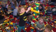 Kinder spielen auf einer großen Fläche voll mit Duplo-Bausteinen