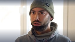 "Tarek rollt" - alias Darek Chikh sitzt mit Wollmütze vor einem Fenster und beantwortet Fragen der ARD für eine Dokumentation über ihn. 