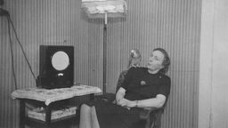 Frau mit Papagei auf der Schulter vor einem Radio ('Volksempfänger'). - Foto, undatiert, 30er Jahre
