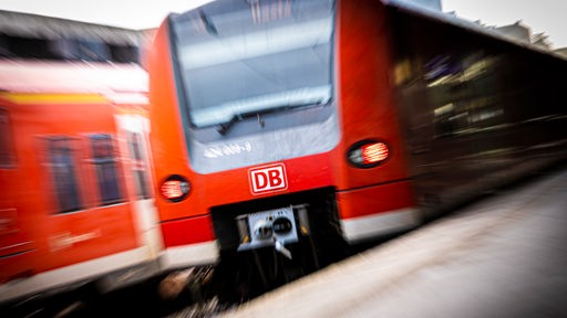 Eine rote Regionalbahn der Deutschen Bahn fährt in einen Bahnhof ein, vom Bahnsteig aus fotografiert.
